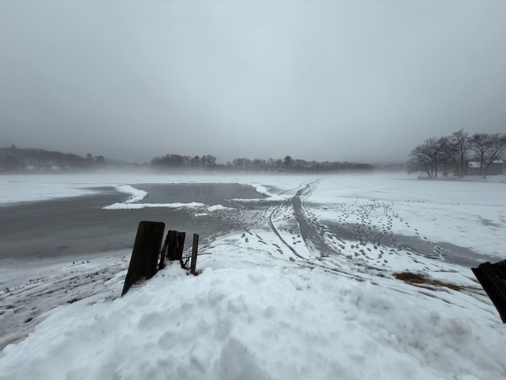 Scenic winter view of Lake Ripple in Grafton, Massachusetts, covered in ice, snow, and light fog